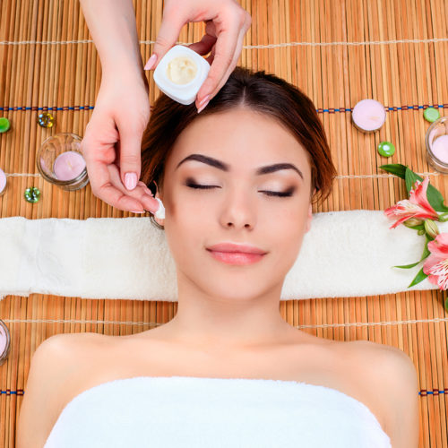 Beautiful young woman at a spa salon resting on a straw mat. Concept of body care and relaxation